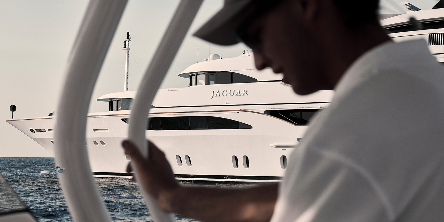 A man on a boat with the Jaguar yacht in the background